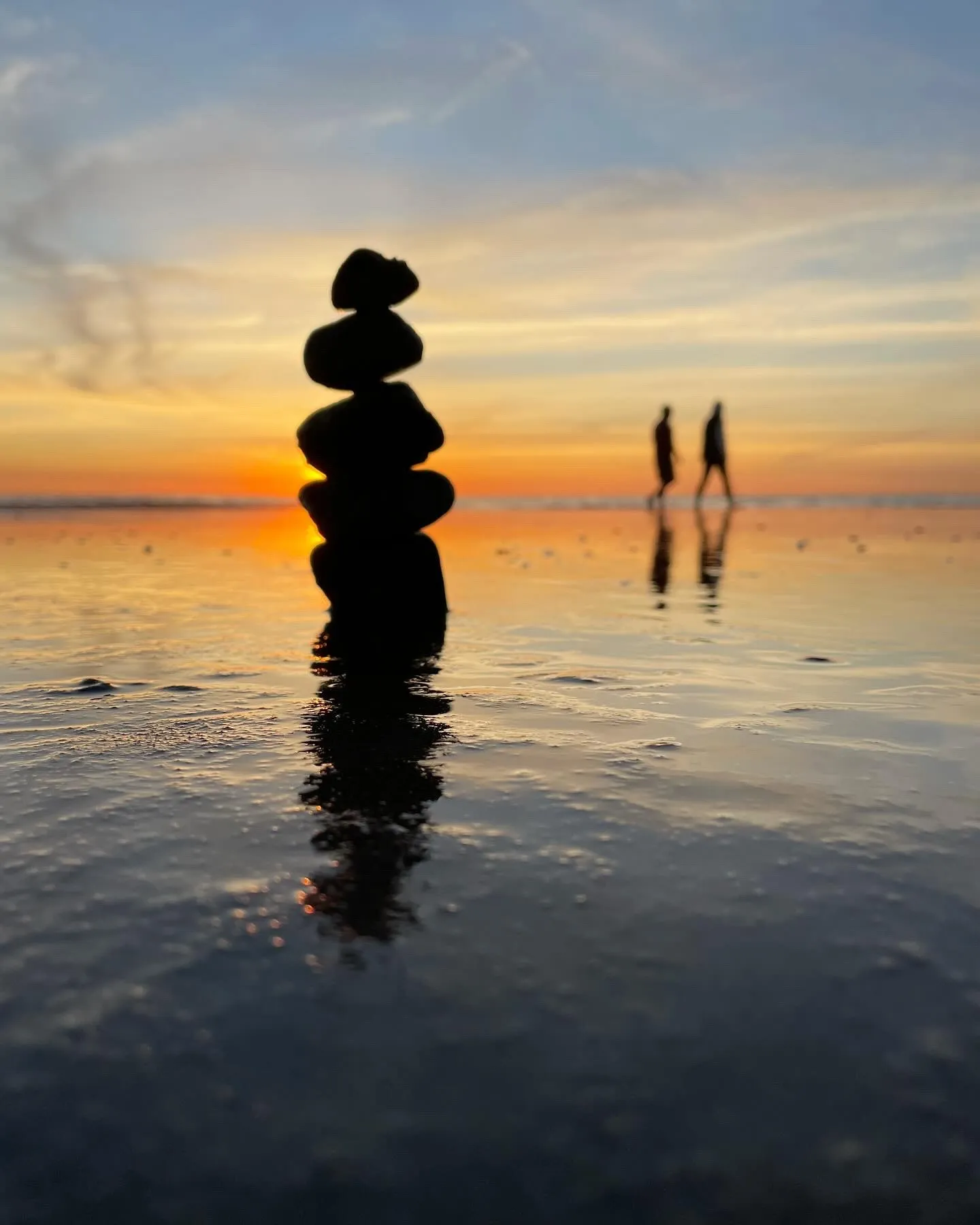 A dark stone tower and two figures appear in a glowing sunset reflection.