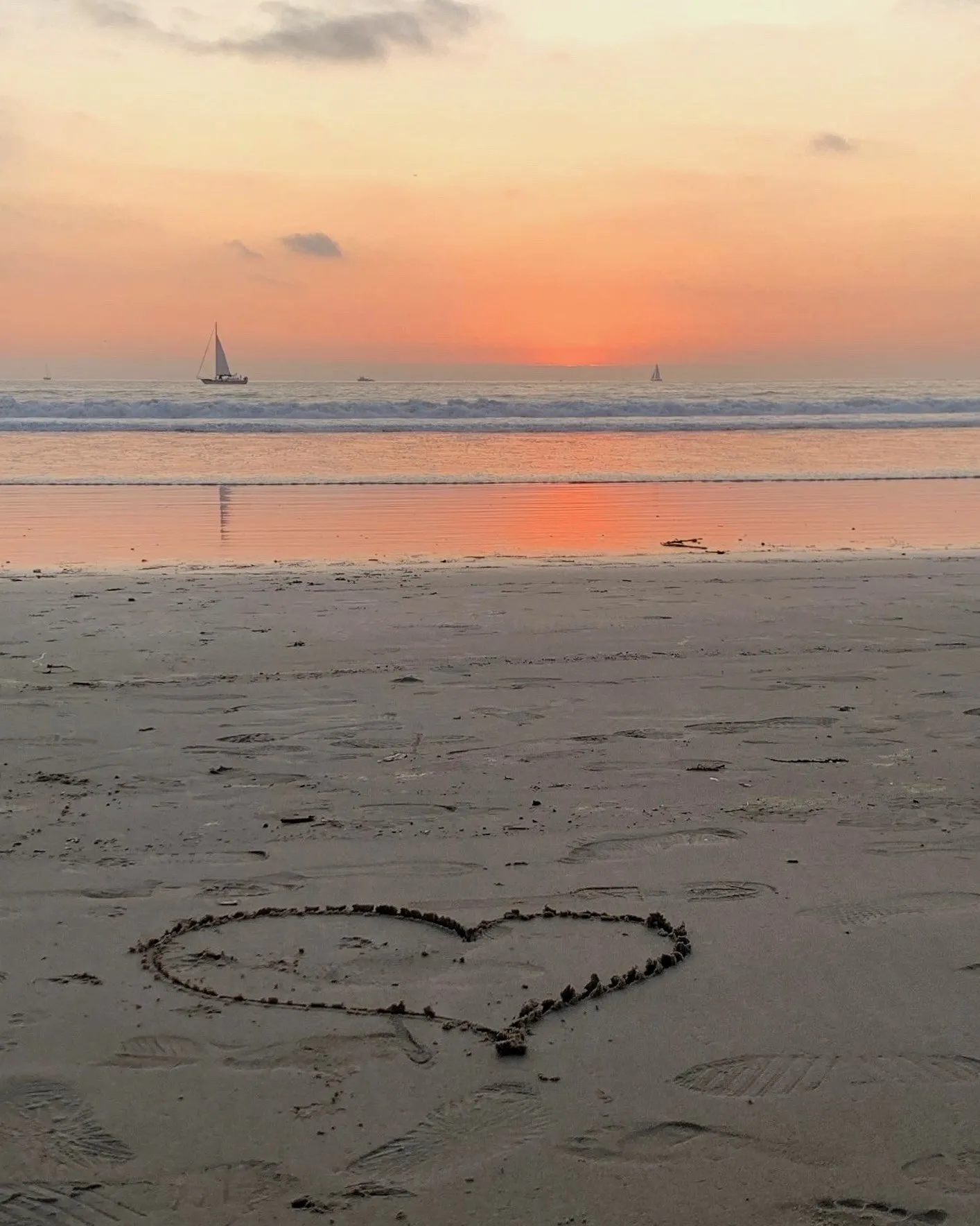 A heart traced in sand catches the soft light of the setting sun.