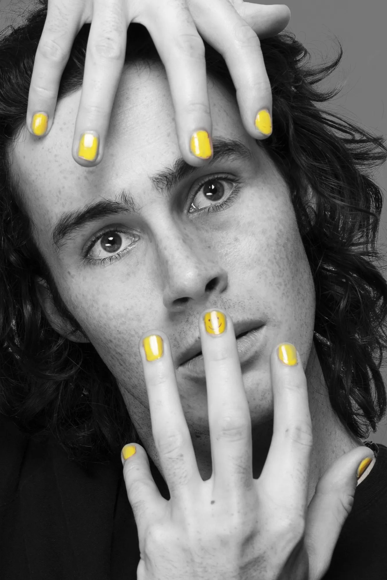 A black-and-white portrait framed by expressive hands.