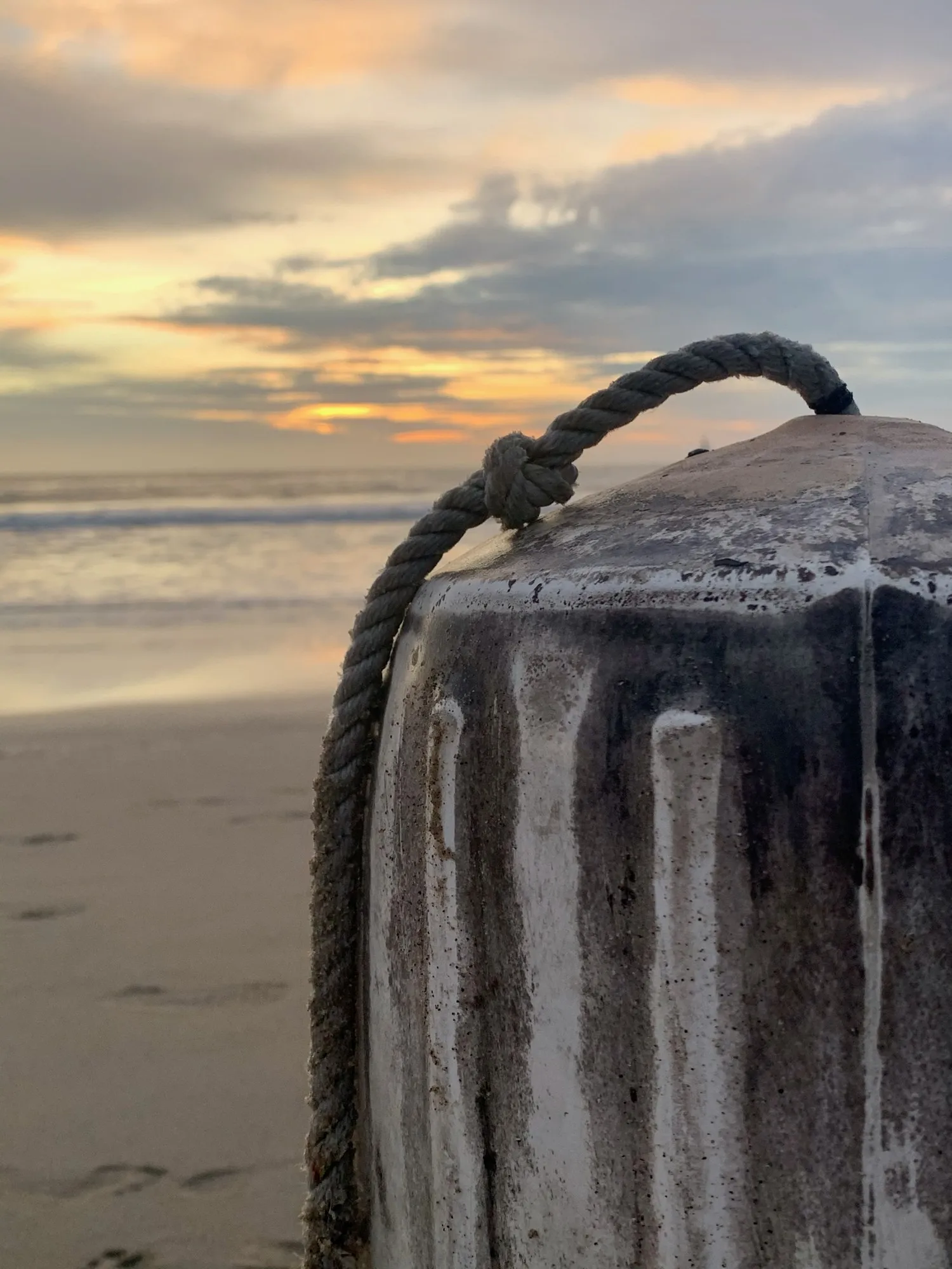 A weathered post and curved fixture beside a clouded sunset