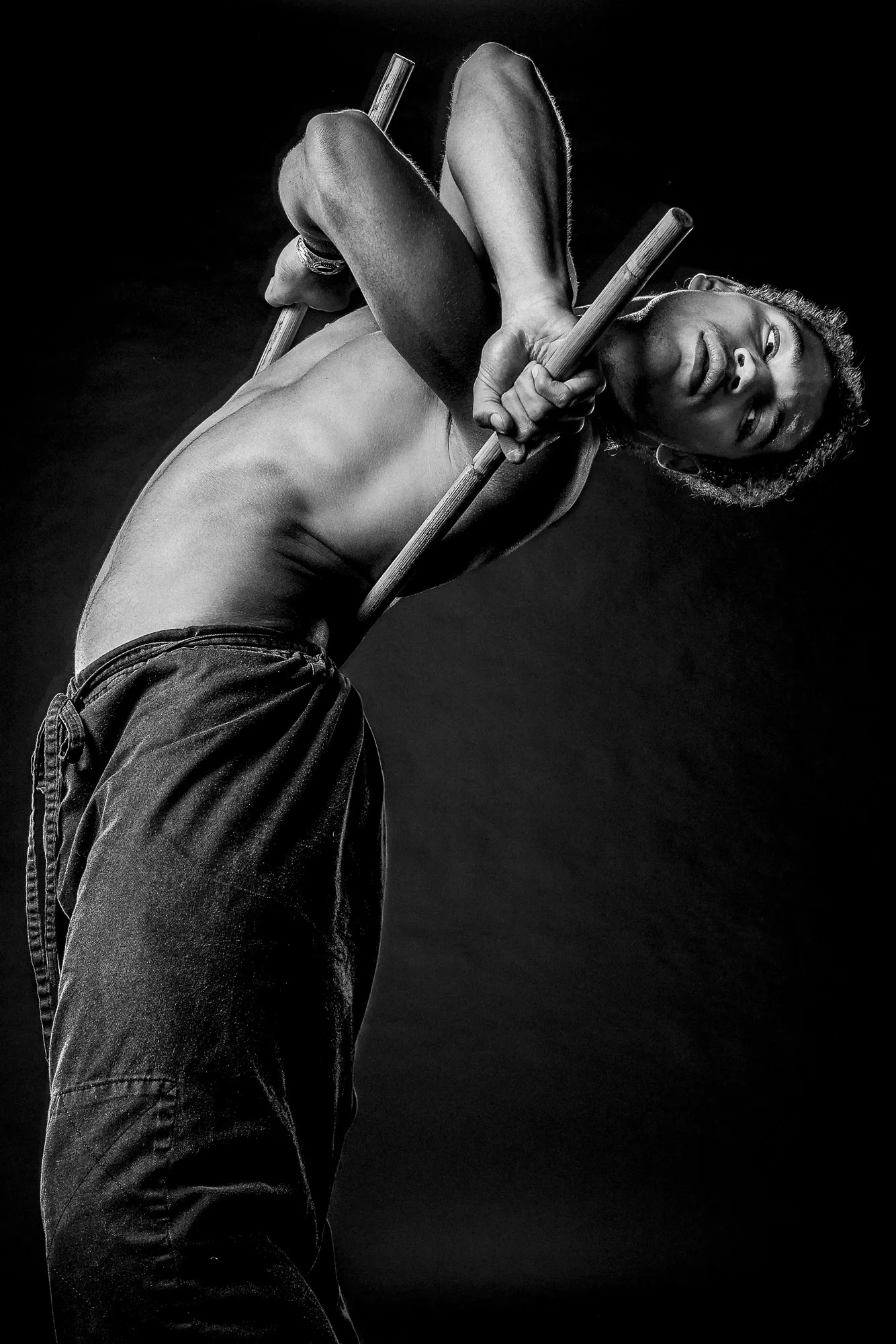 Black-and-white portrait of a dancer holding wooden poles