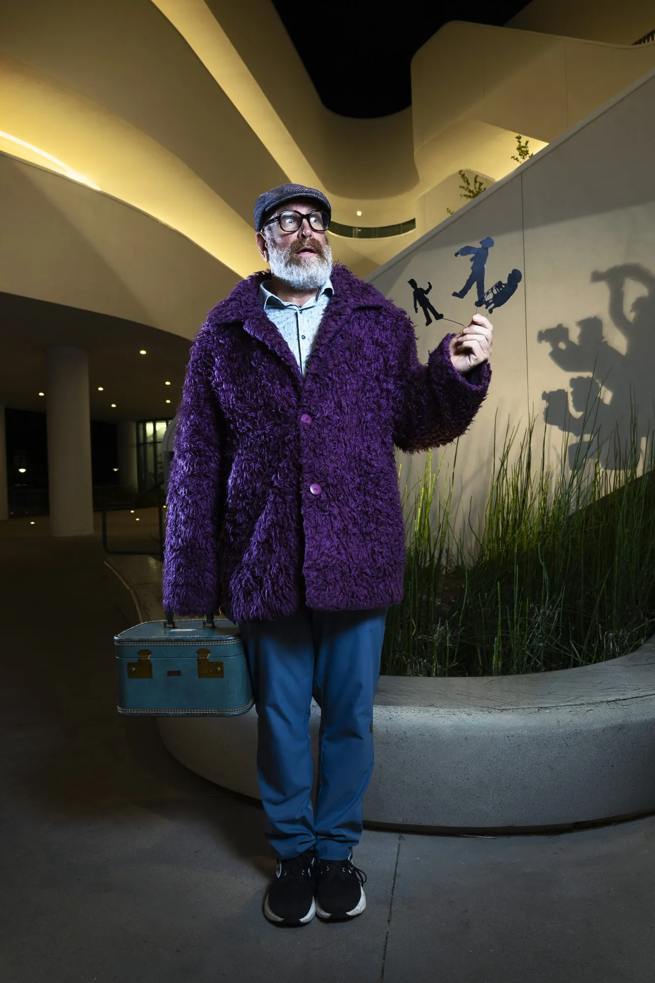A man in a purple jacket beneath a ceiling patterned with large shadows