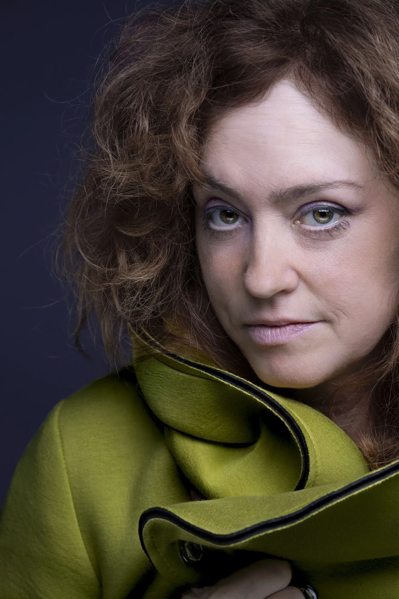 Close portrait of a woman with curly hair wearing a sculptural green collar