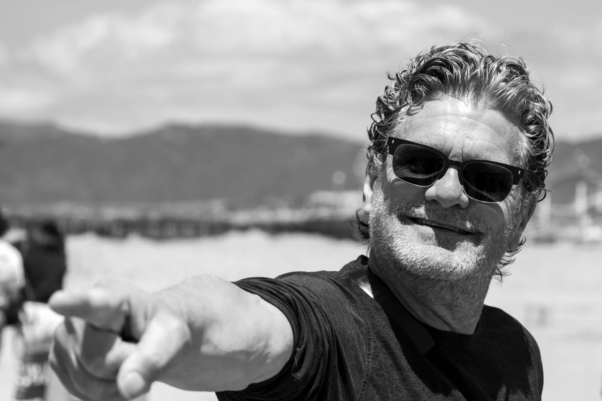 A smiling man in sunglasses photographed in black and white.