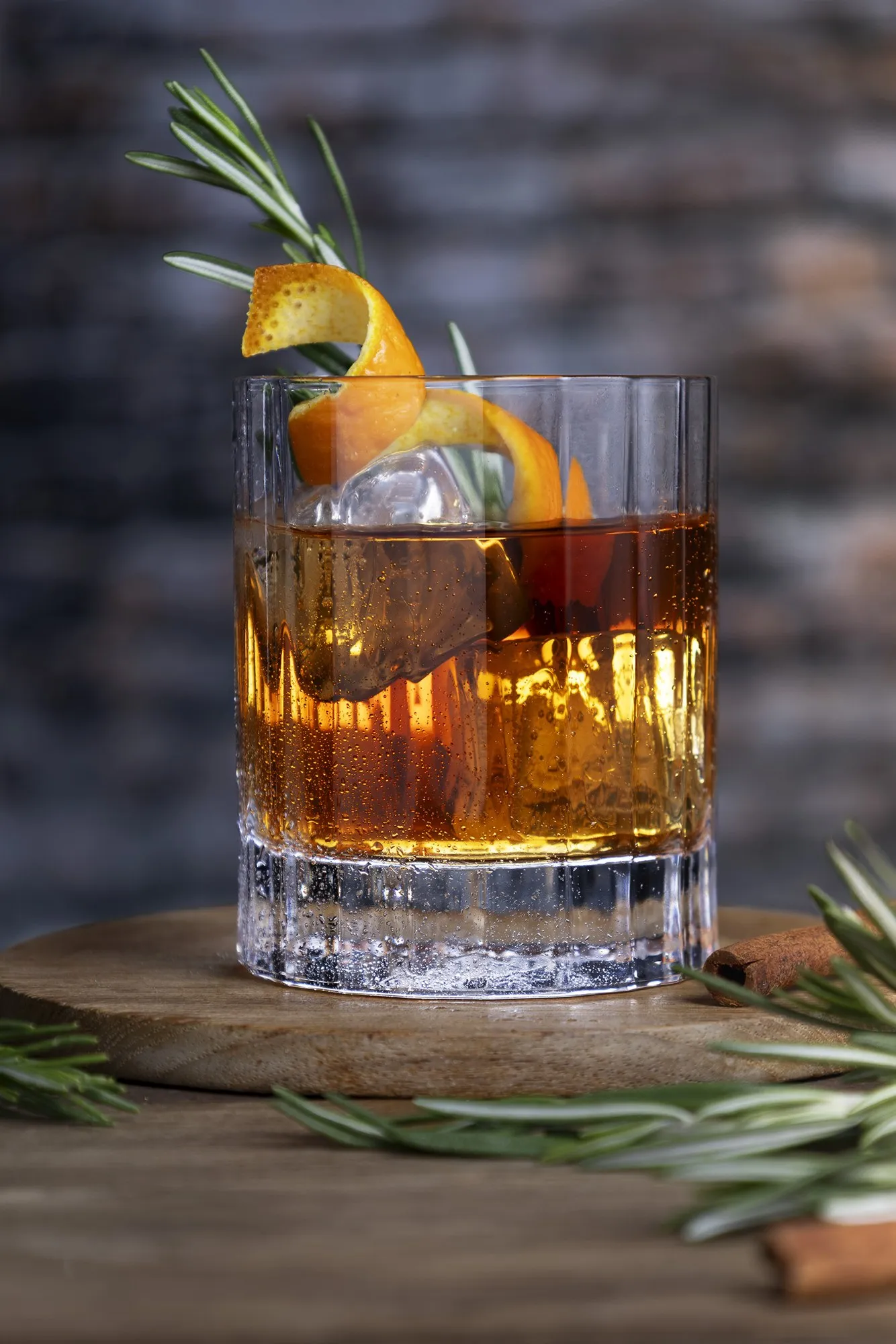 Amber cocktail with an orange garnish on a dark tabletop