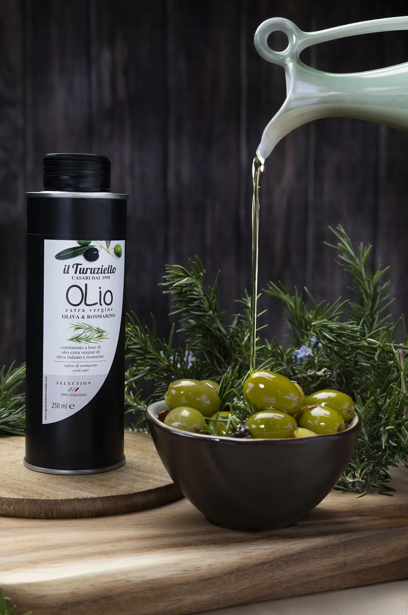 An olive oil bottle beside olives and a glass vessel