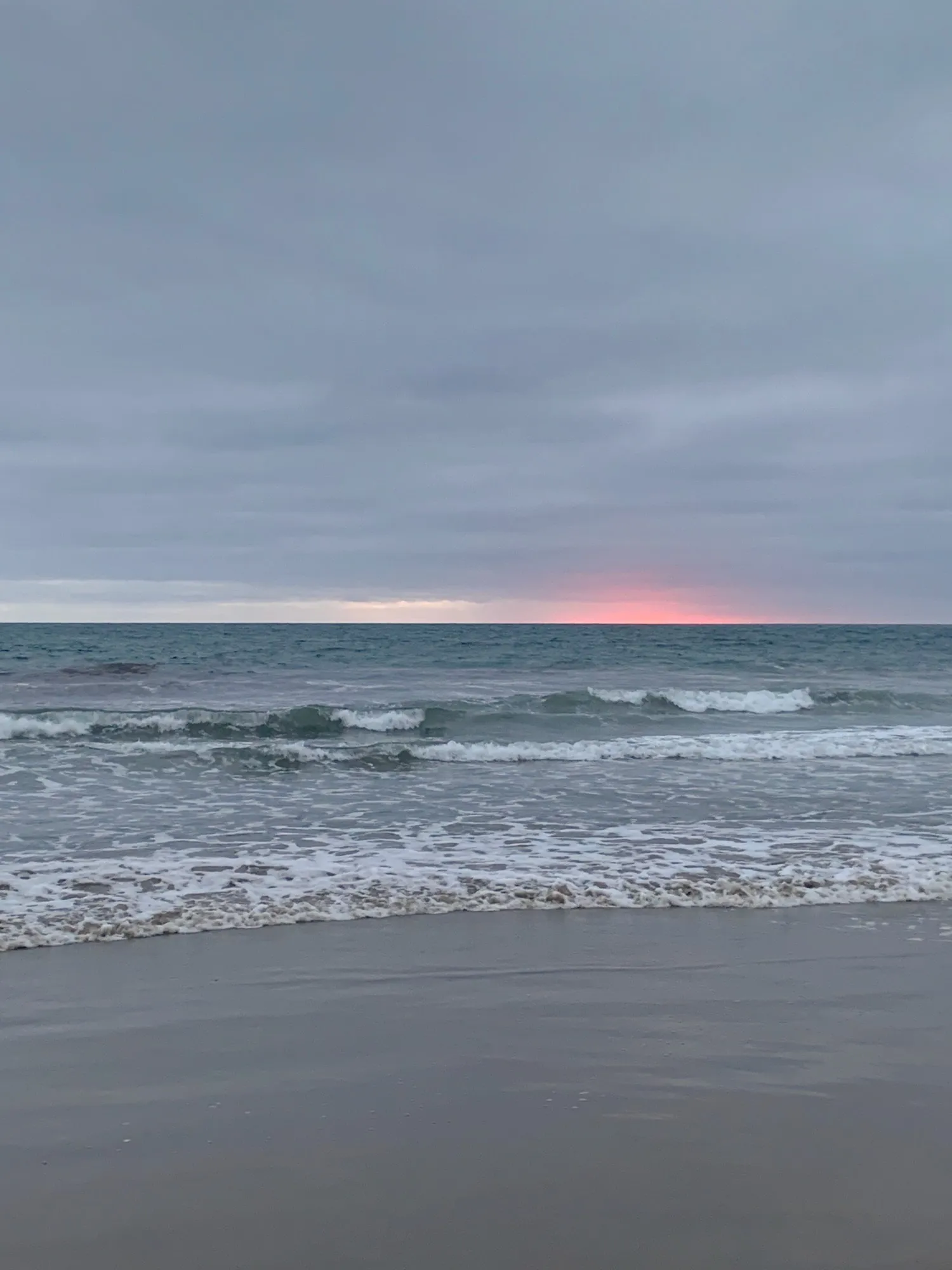 A quiet gray-blue horizon holds a small pink line of sunset.