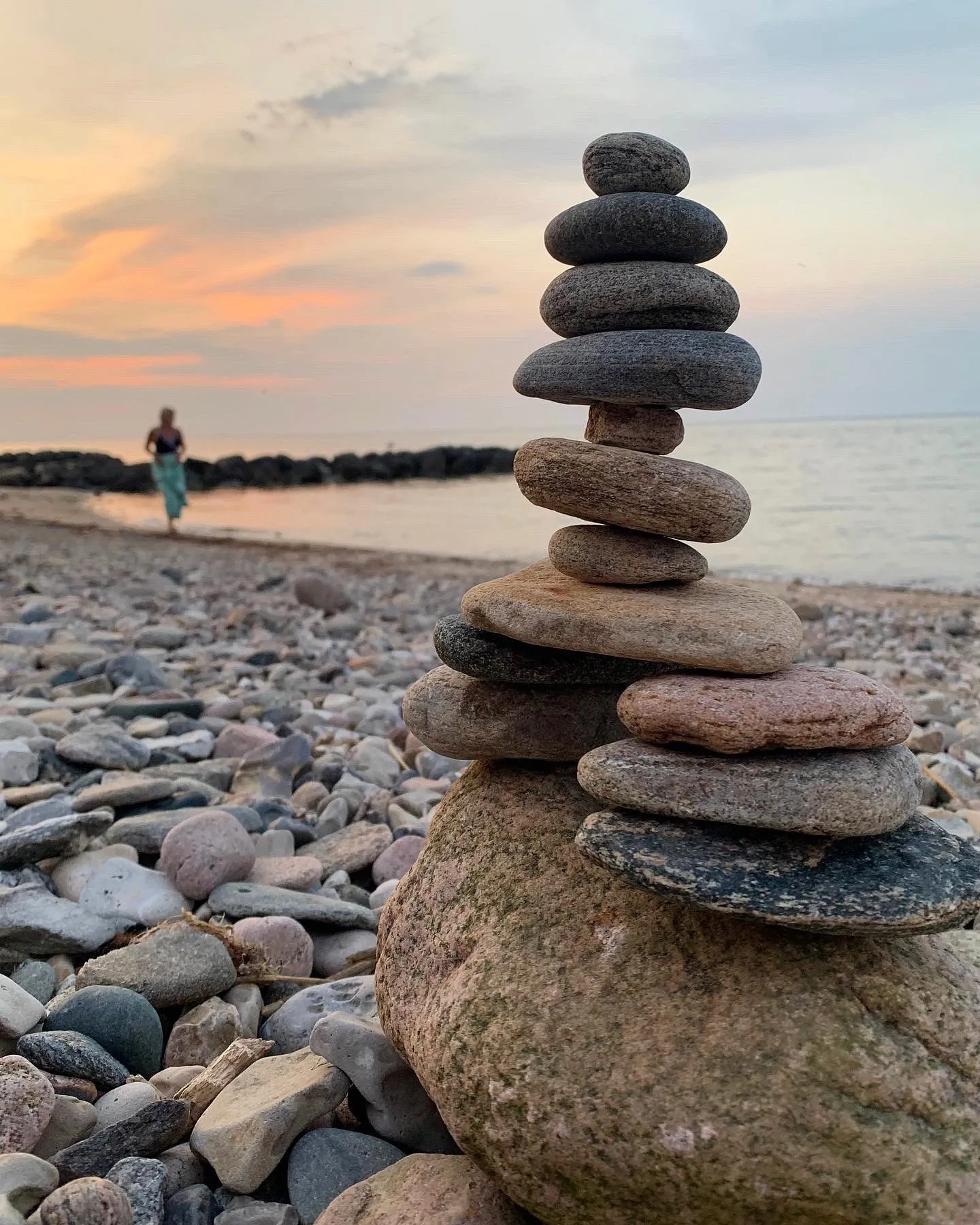 A slender stone tower on the shore beneath a soft orange evening sky