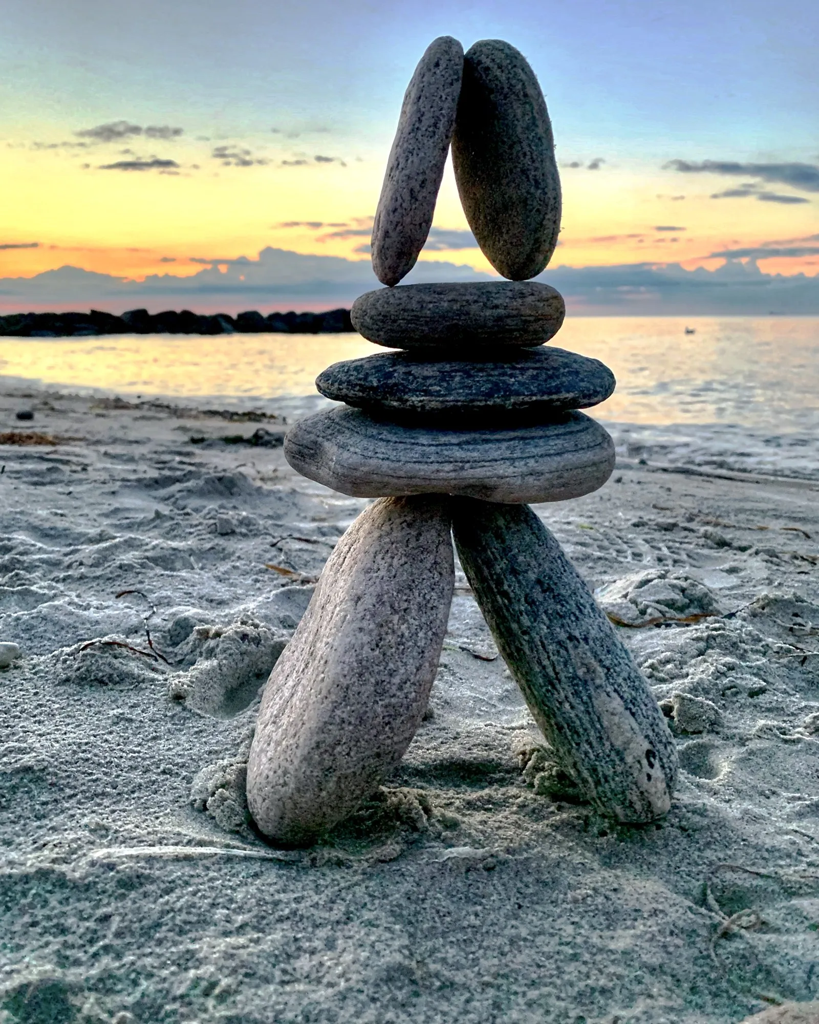 A balanced stone arch above a stack of pebbles at sunset