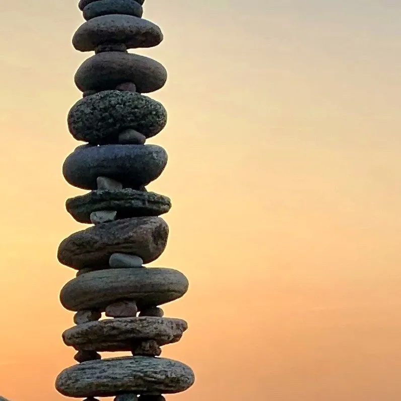 A close view of a tall pebble stack against a golden sky