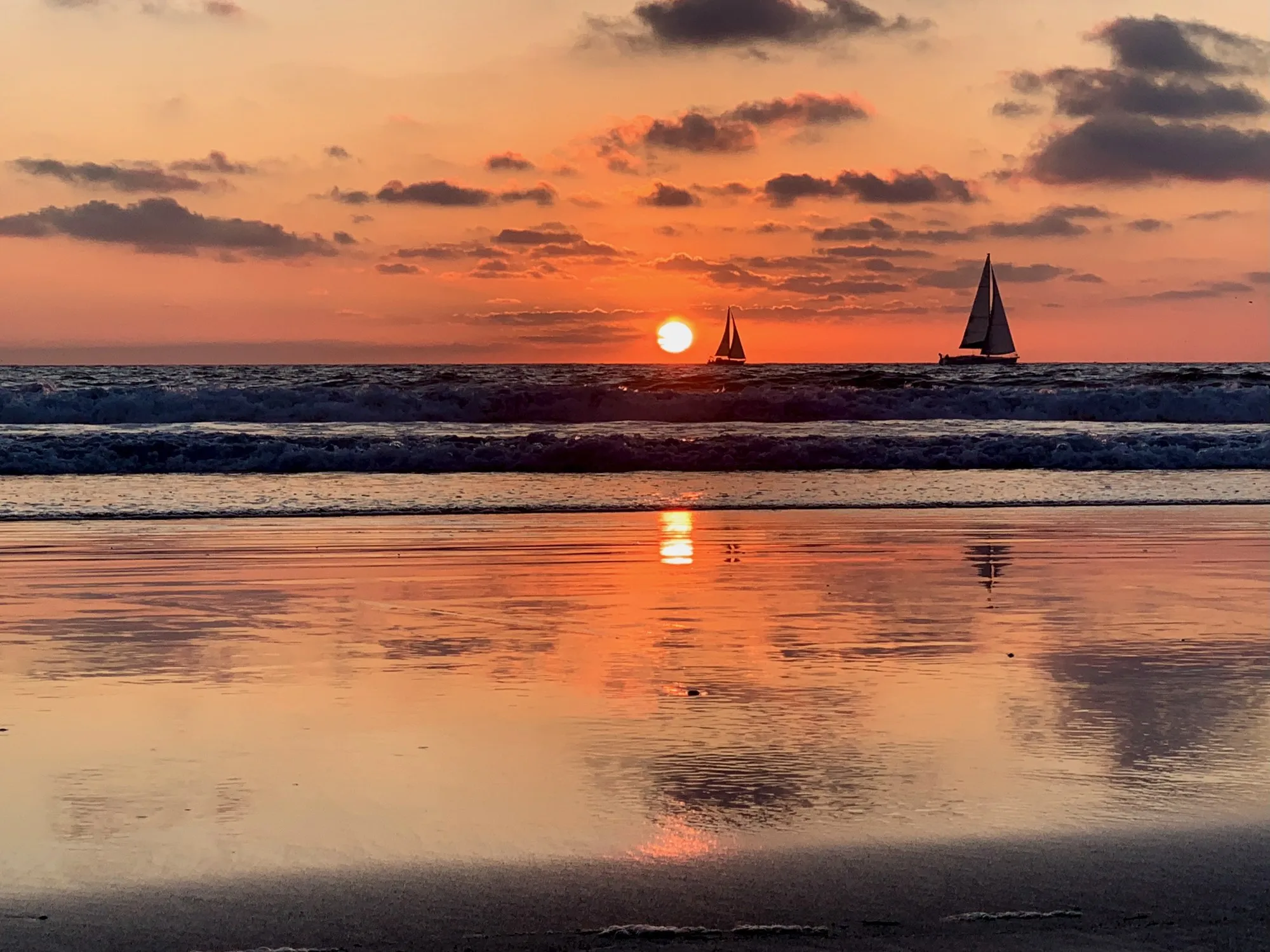 A sailboat crosses the sunset. A beach observation made in the changing evening light.