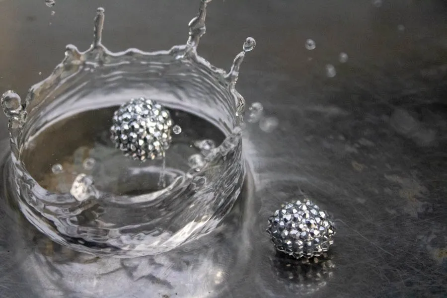 A silver sphere breaks the surface of a sculptural splash of water.