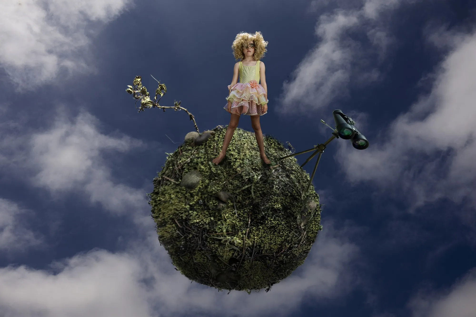 A tiny figure stands on a miniature imagined world beneath a wide sky.