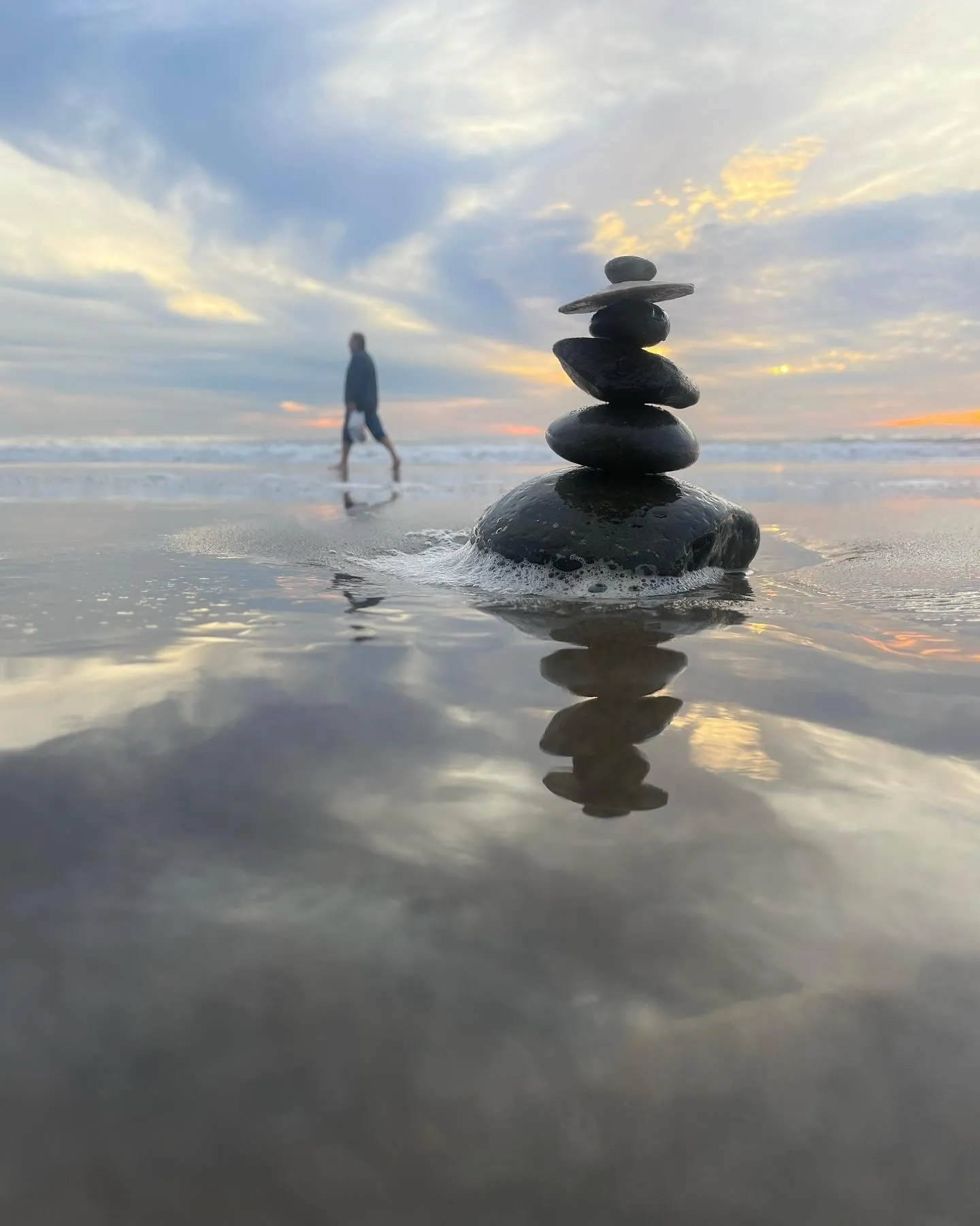 A stone tower and a distant figure reflect in shallow evening water.