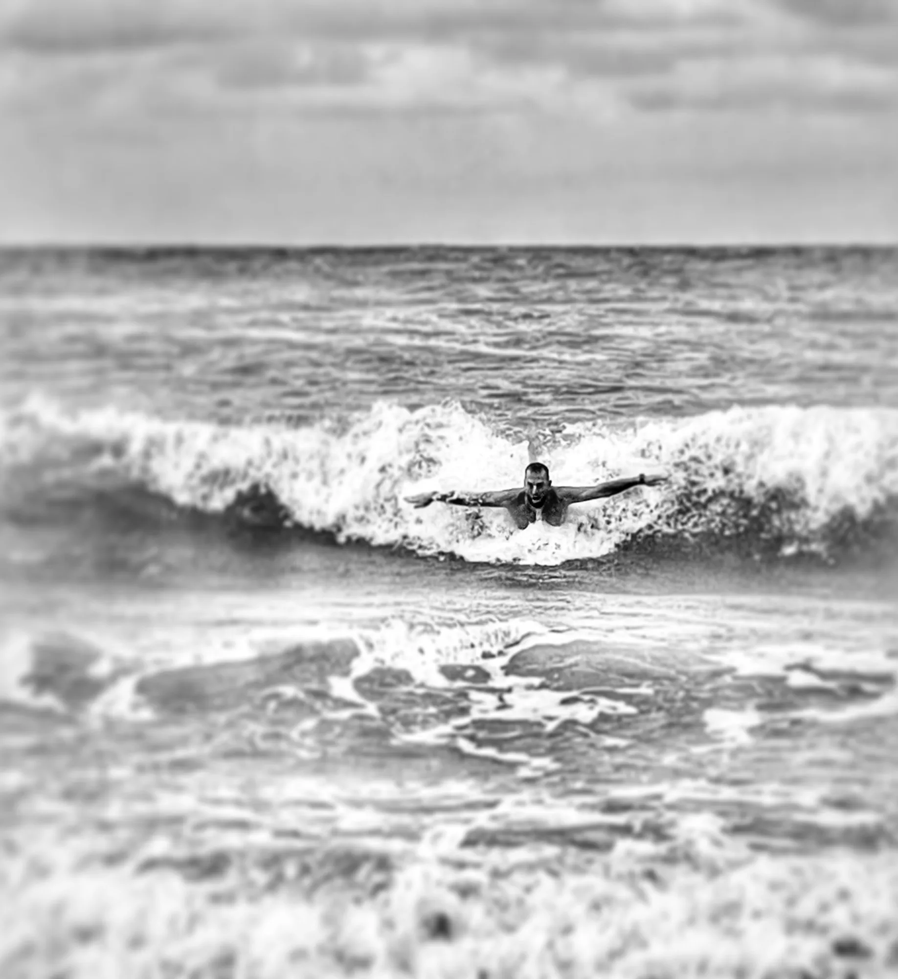 A surfer cuts across a breaking wave in a black-and-white photograph.
