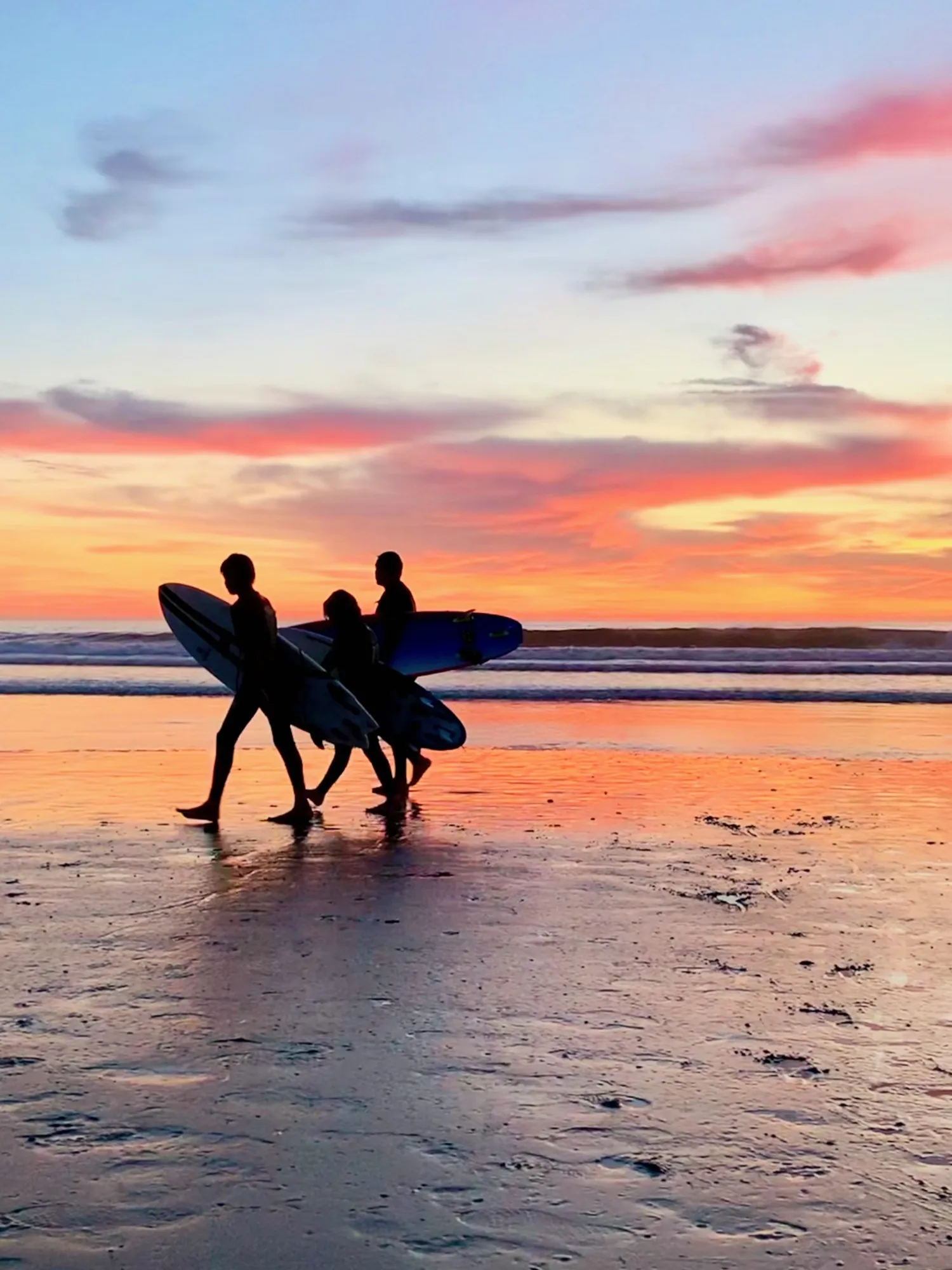 Three people walking the shoreline. A beach observation made in the changing evening light.