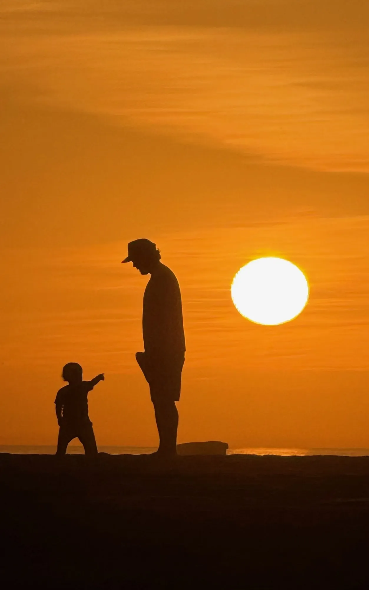 Two figures silhouetted by the sunset. A beach observation made in the changing evening light.