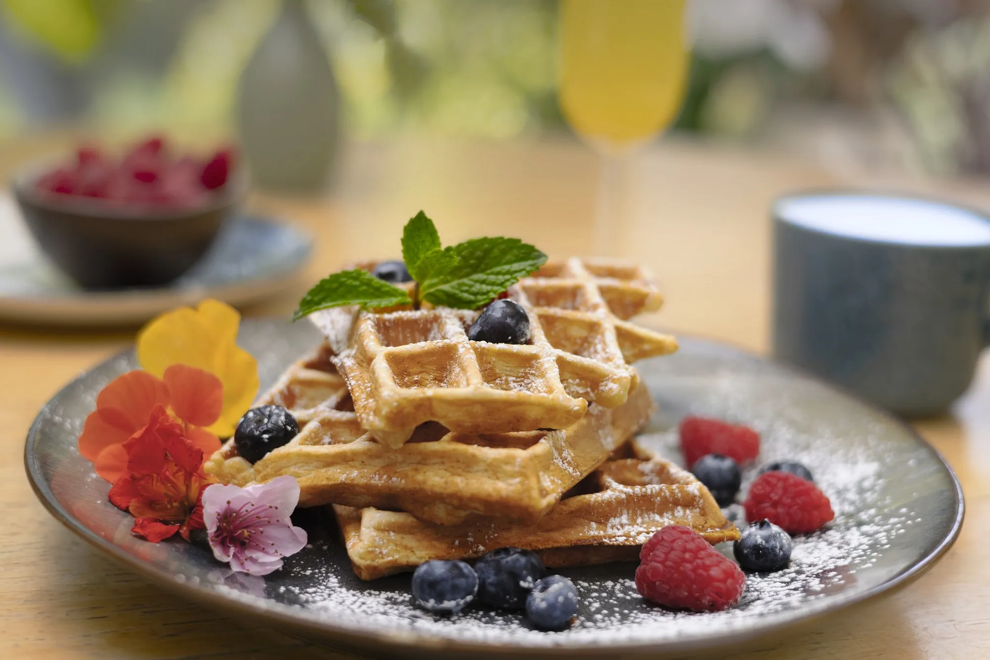 A waffle topped with berries and fruit sits on a white breakfast plate.