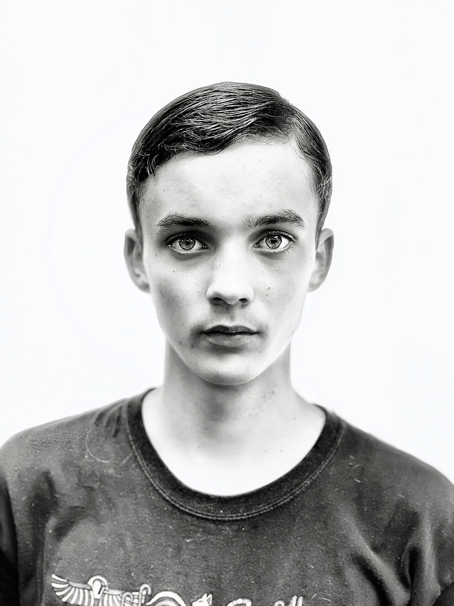 A young man faces the camera in a simple black-and-white portrait.